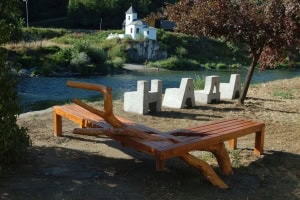 Rustieke houten bank en creatieve ‘H A A A’ kunst in natuursetting langs rivier.