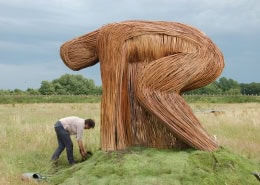 Unieke houten kunstinstallatie in een open veld.