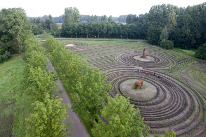 Uitzicht vanaf de lucht van een park met sierlijke labyrinten en groen omliggende bomen.